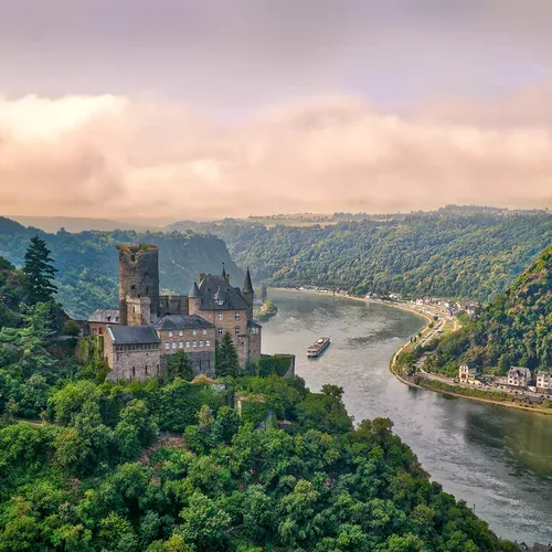A river cruise ship passing a hilltop castle along the Rhine in Europe